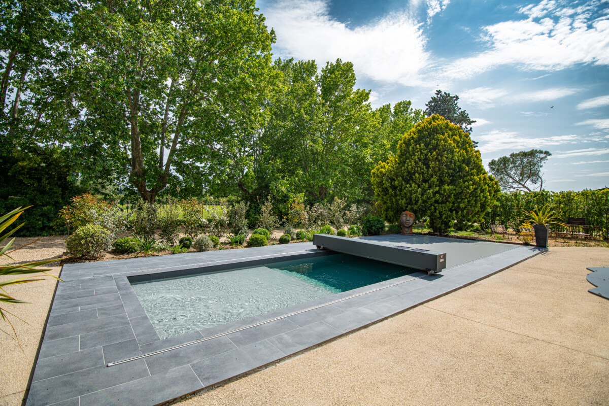 Luxe terras met houten vloer, zwembad, witte ligstoelen en groene planten, grenzend aan een modern huis met grote ramen.